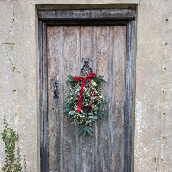 The finished piece, a festive alternative to the Christmas Wreath, the stunning festive Christmas Swag hanging on a rustic wooden door