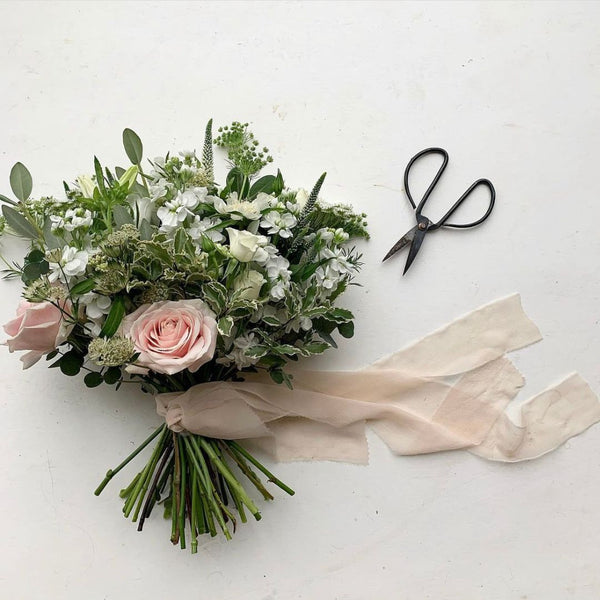 Pod & Pip's bridal bouquet, laid out on a marble worktop alongside scissors and ribbon